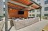 Inviting outdoor entertainment area with spacious seating, modern wood-panel accents, and a large TV under a stylish pergola.