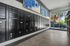 Elegant apartment mailroom with sleek black mailboxes, modern tiled flooring, and large windows offering natural light and outdoor views.