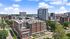 Vibrant urban skyline featuring modern apartments, lush greenery, and lively cityscape under a bright blue sky.