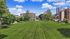 Expansive green park surrounded by modern apartment buildings under a vibrant blue sky.