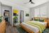 Bright and modern apartment bedroom with sleek wooden furniture, vibrant decor, and ample natural light.