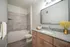 Modern bathroom featuring a sleek granite countertop, elegant light fixtures, and a luxurious tiled shower. Perfect blend of style and comfort.