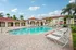 Inviting apartment complex featuring a sparkling swimming pool, surrounded by palm trees and comfortable loungers, under a bright blue sky.