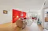 Inviting living room with vibrant red accent wall, cozy seating, and ample natural light, perfect for relaxation and entertainment.
