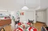 Inviting open-plan dining and living area with stylish decor, featuring a glass dining table set, cozy brown sofa, and natural light from large windows.