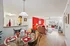 Inviting open-concept living space featuring a vibrant red accent wall, elegant dining area, and cozy seating with ample natural light.