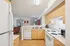 Bright and inviting kitchen space featuring modern appliances, warm wooden cabinetry, and a view into the cozy living room.