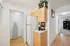 Charming apartment corner featuring a contemporary kitchen setup with wooden cabinetry, sleek counter space, and modern appliances. Bright hallway leads to a cozy laundry area and a beautifully arranged living space with shelving.