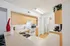 Modern kitchen with light wood cabinets, white appliances, stylish countertop, and vibrant decor featuring a red vase and greenery.