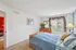 Inviting bedroom with cozy blue bedding, elegant wood furniture, and natural light streaming through large windows with garden views.