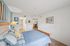 Inviting bedroom with a cozy blue-striped bedspread, soft lighting, and a glimpse into a spacious bathroom, perfect for relaxation.