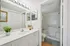Bright and elegant bathroom with a large vanity mirror, sleek white countertop, and inviting bathtub.