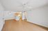 Bright and inviting open-concept living space with sleek wooden floors, featuring a modern kitchen and ceiling fan.