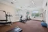 Bright and airy fitness center with modern cardio equipment, large windows, and a wall-mounted TV creating an inviting workout environment.