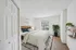 Inviting bedroom with a cozy beige bed, stylish decor, and a large window offering lush garden views.