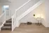 Modern townhome interior featuring sleek staircase, cozy workspace under stairs with stylish chair, desk lamp, and decorative plant.