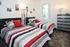 Charming bedroom with twin beds, stylish striped bedding, modern lamp, and vibrant decor creating a cozy atmosphere.
