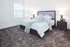 Inviting bedroom with plush carpet, modern queen bed, and soft lighting, creating a serene retreat.