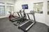 Modern apartment gym featuring state-of-the-art treadmills, an elliptical, and a sleek red exercise bike, offering a bright and motivating workout environment.