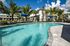 Townhome community with a sparkling pool surrounded by palm trees and comfortable lounge chairs, creating a perfect tropical retreat.