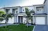Modern townhouse with sleek grey exterior, featuring manicured landscaping and inviting balconies, perfect for stylish suburban living.