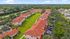 Charming community view featuring Mediterranean-style townhouses with red tiled roofs, surrounded by lush greenery and palm trees.
