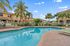 Inviting poolside oasis with palm trees and elegant townhouses, perfect for relaxation and an upscale lifestyle.