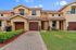 Charming townhouse with a warm beige exterior, tiled roof, and welcoming entrance. Features a manicured lawn and a paved driveway, embodying suburban serenity.