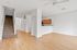 Modern open-concept apartment interior with elegant wood flooring, cozy carpeted staircase, and bright natural light.