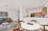 Chic open-concept living area with a stylish dining table, cozy seating, and modern kitchen with wooden cabinets.