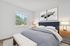 Bright and cozy bedroom with a contemporary design, featuring a plush bed, elegant artwork, and abundant natural light from a large window.