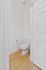 Bright, modern bathroom with sleek white fixtures, a wooden floor, and minimalist design creating a fresh ambiance.