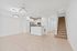 Bright open-concept living and kitchen space featuring sleek white cabinetry, modern fixtures, and elegant tiled flooring with a staircase leading to the upper level.