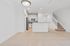 Modern open-concept kitchen and dining area with sleek tile flooring and elegant white cabinetry, adjacent to a stylish staircase.