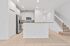 Modern kitchen with sleek stainless steel appliances, elegant white cabinetry, and a cozy staircase leading upstairs.