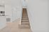 Inviting hallway with elegant tiled flooring and plush carpeted stairs leading to a bright, airy second floor.