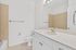 Bright and modern bathroom with elegant fixtures, featuring a sleek vanity, large mirror, and pristine tilework.
