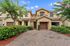 Charming townhouse with attractive facade, lush landscaping, and a welcoming driveway under a clear blue sky.