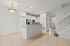 Contemporary kitchen with sleek stainless steel appliances, elegant white cabinetry, and stylish lighting in an open-concept living space featuring a chic staircase.