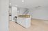 Modern open-plan kitchen and living area with elegant granite countertops, bright tiled floors, and a staircase leading to the upper level in a spacious apartment.