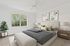 Inviting bedroom with elegant decor, featuring a plush bed adorned with stylish cushions, large window offering natural light, and chic artwork on the wall.