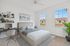 Bright and modern bedroom with elegant furnishings, large windows, and a built-in workspace, offering a serene and stylish living environment.