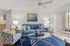 Bright and stylish living room featuring a cozy blue sofa, modern glass coffee table, and large sliding doors with natural light.
