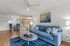 Inviting living room with modern decor featuring a cozy blue sofa, abstract art, and glass coffee table, seamlessly flowing into a stylish dining area.