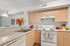 Bright and modern kitchen with light wood cabinetry, sleek countertops, and a charming dining nook accentuated by vibrant decor.