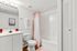 Bright and inviting bathroom with modern fixtures, chic pink accents, and ample storage space.