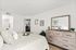 Inviting bedroom with cozy decor, featuring a patterned bedspread, elegant dresser with mirror, and tasteful wall art.