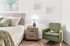 Charming bedroom interior featuring a cozy bed with plush pillows, elegant nightstand with ambient lamp, and a stylish green armchair, perfect for relaxation.
