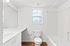 Bright modern bathroom with sleek fixtures, featuring a large mirror, elegant vanity, and a chic combination of bathtub and shower.