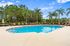 Luxury pool area surrounded by lush greenery and palm trees, featuring stylish lounge chairs under a clear blue sky.